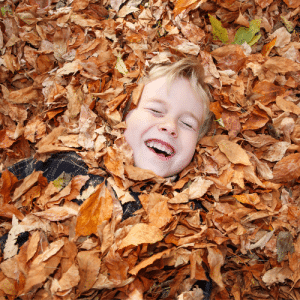child in fall leaves on lawn